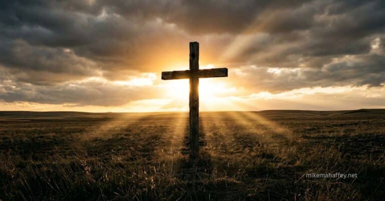 A weathered wooden cross standing alone in an open field with light breaking through heavy clouds directly behind it