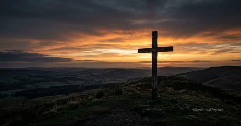 A wooden cross silhouetted at dawn against a sky moving from darkness to golden light, representing reconciliation through the blood of Jesus.