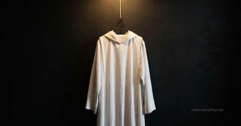 A spotless white robe illuminated against darkness, representing the cleansing from sin described in Revelation 7:14 — robes washed white in the blood of the Lamb.