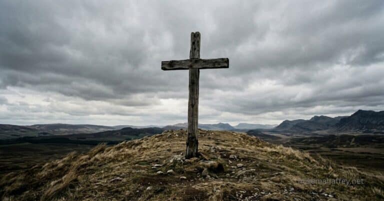 A weathered wooden cross standing alone under an overcast sky, representing the weight of sin and the necessity of what Christ accomplished at the Cross.