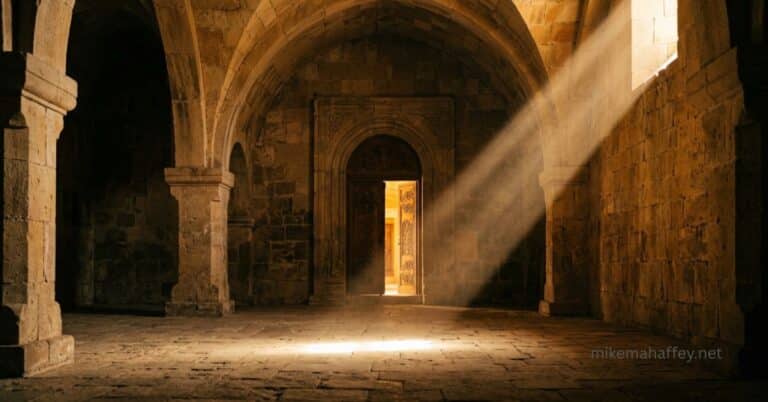 A shaft of golden light cuts through a vaulted stone chamber toward an open doorway, picturing how God sees the blood of Jesus continuously, even when no one is watching.