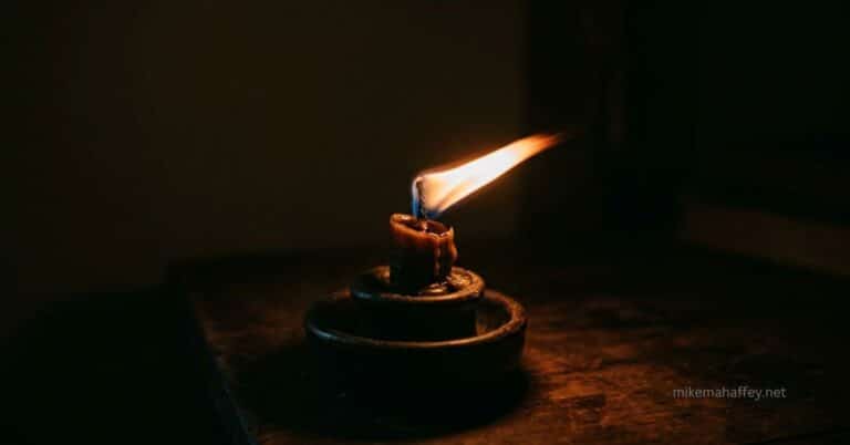 A small candle flame bends sideways in a dark room, still burning but disturbed — a picture of how the Holy Spirit can be grieved without ever going out.