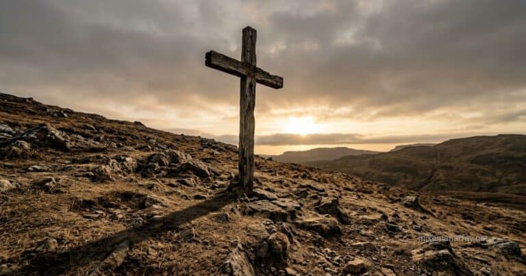 A weathered wooden cross stands on a rocky hillside as sunrise breaks through clouds on the horizon, a picture of the price paid through the blood of Jesus.
